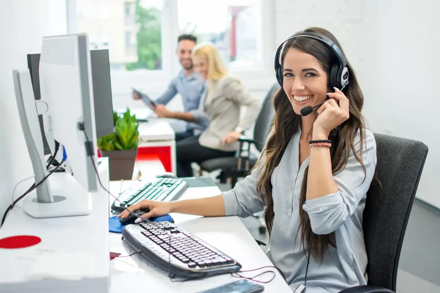 Junge Frau mit Headset sitzend an Schreibtisch