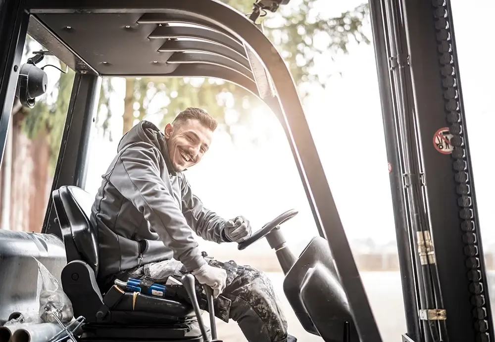 Junger Mann in Arbeitskleidung in Gabelstapler