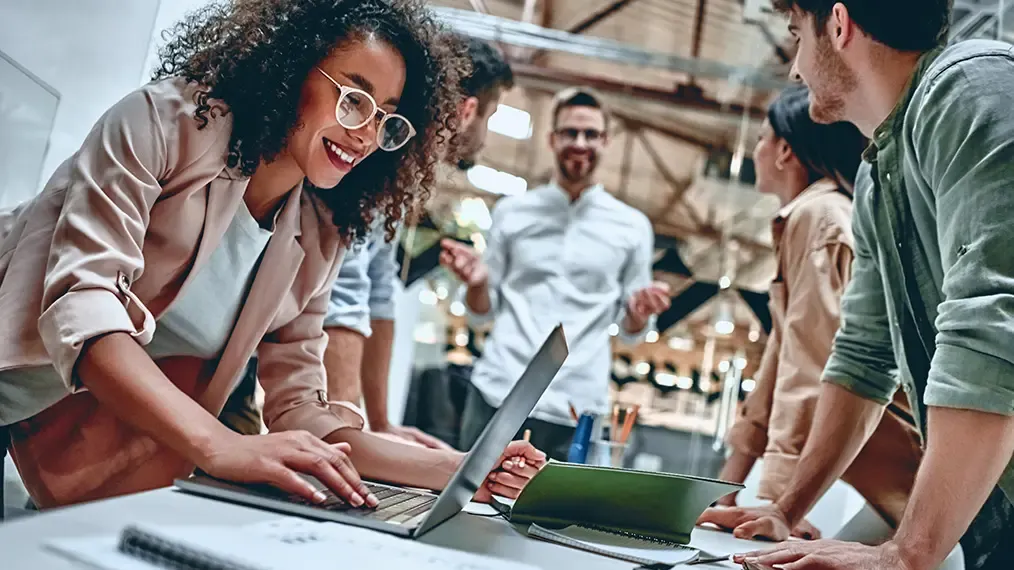 Teamarbeit stehende Gruppe um einen Schreibtisch