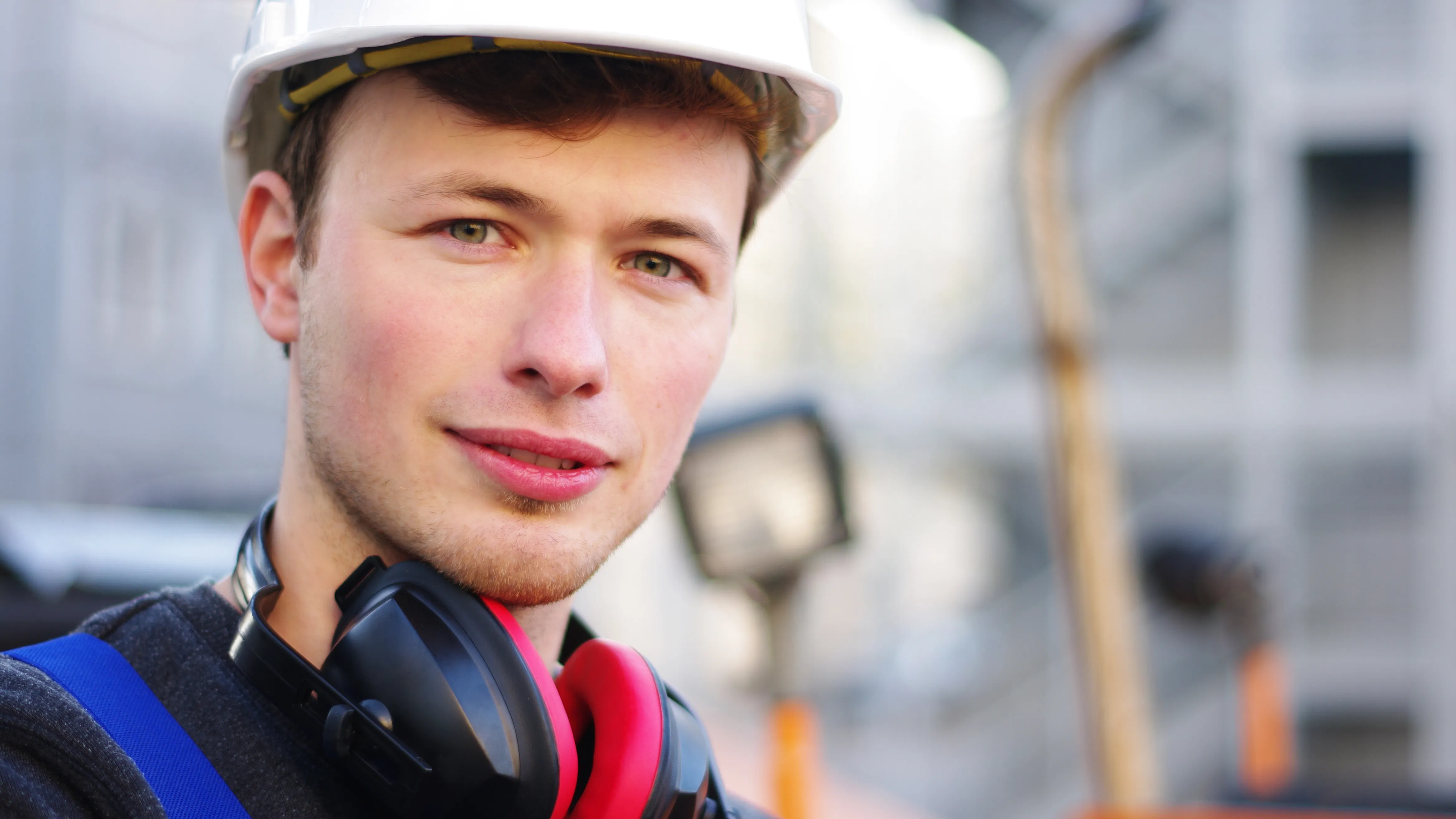 Junger Mann mit Helm und Kopfhörern lächelt in die Kamera