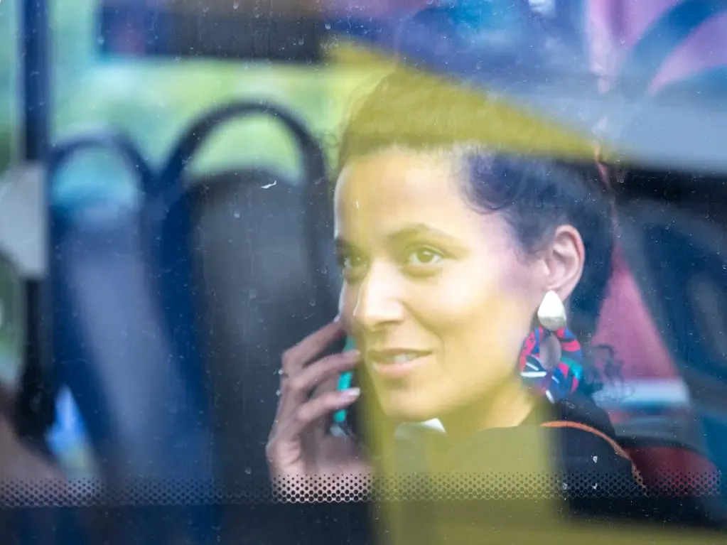 Frau mit Smartphone schaut aus dem Fenster eines Busses