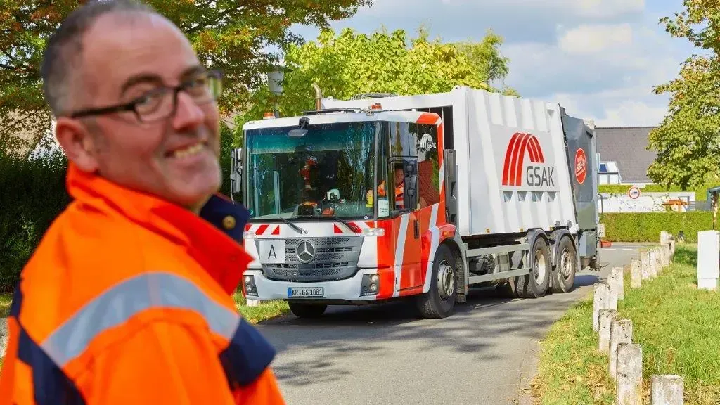 GSAK Mitarbeiter steht im Vordergrund und ein Entsorgungsfahrzeug steht hinten