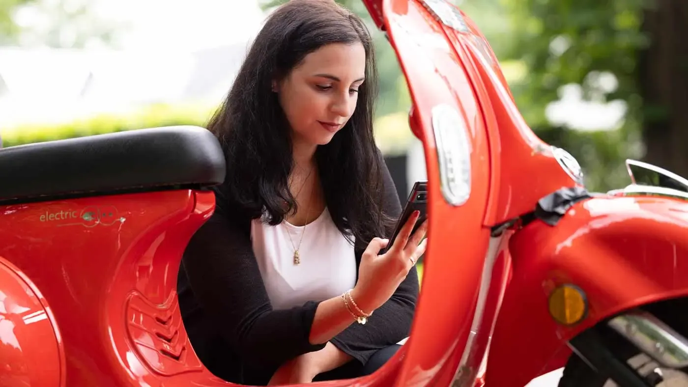 Junge Frau mit Smartphone neben SWK KRuiser
