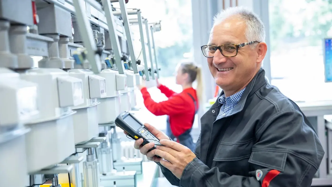 NGN Kollege mit Prüfgerät in der Hand lächelt in die Kamera