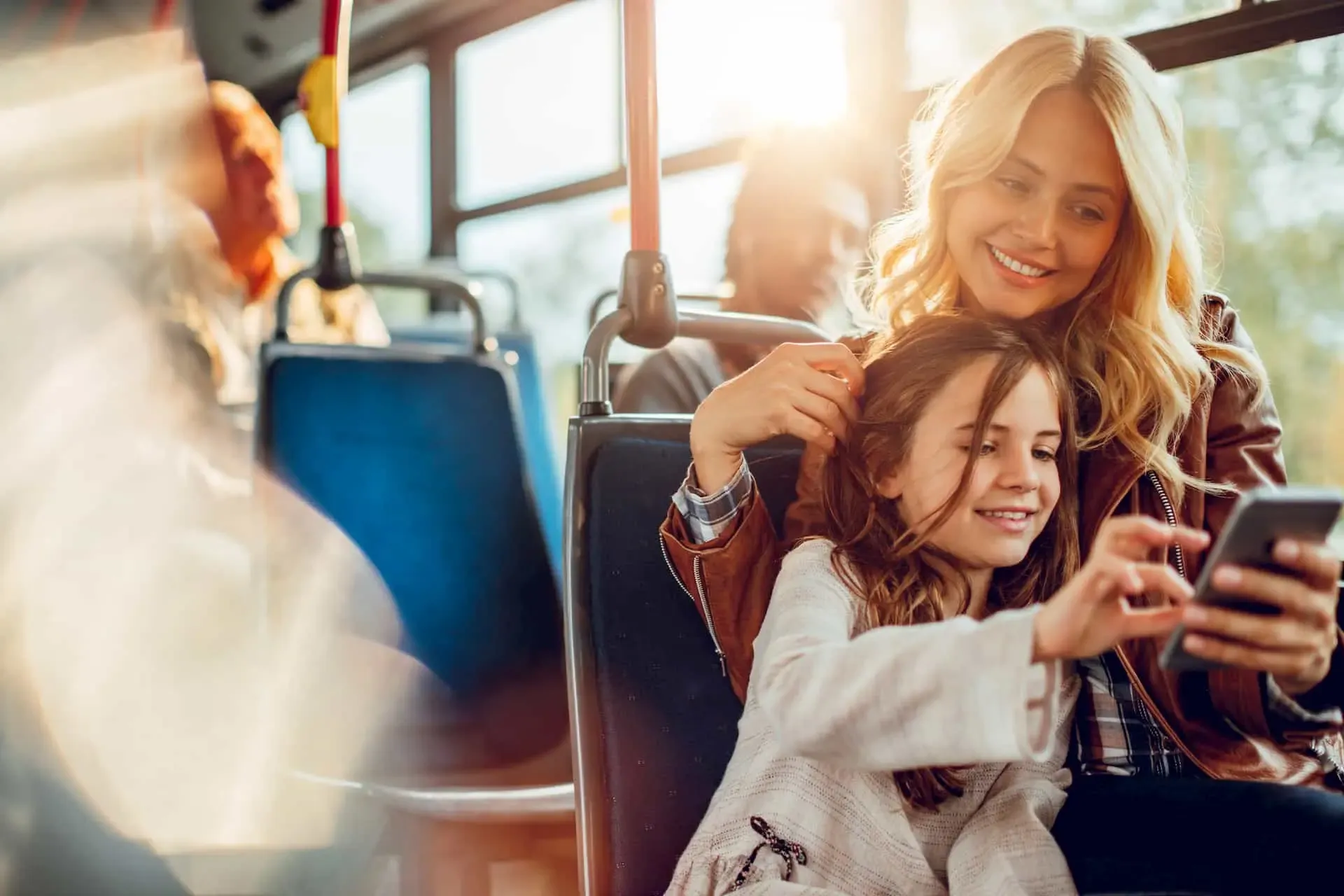 Mutter und Tochter schauen auf ein Smartphone im Bus