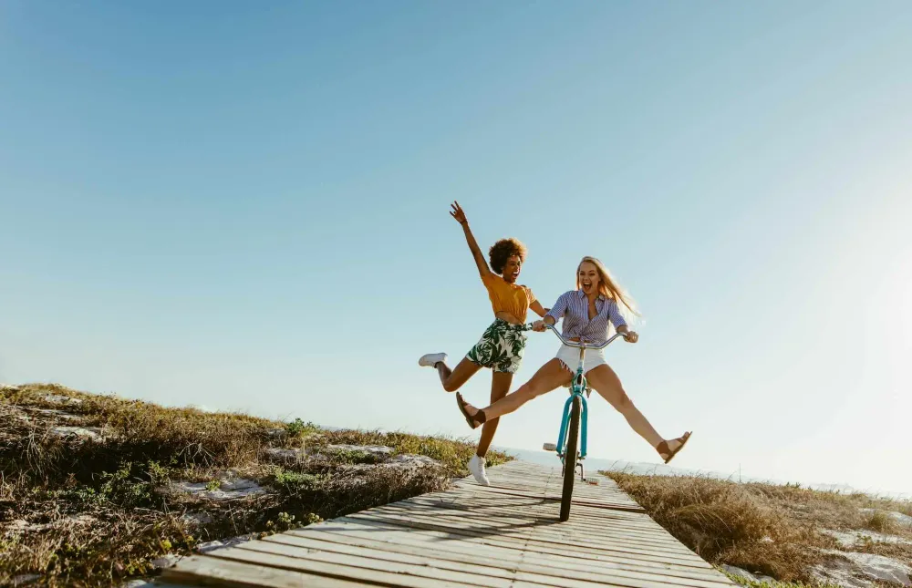 Zwei Frauen springen am Strand in die Luft