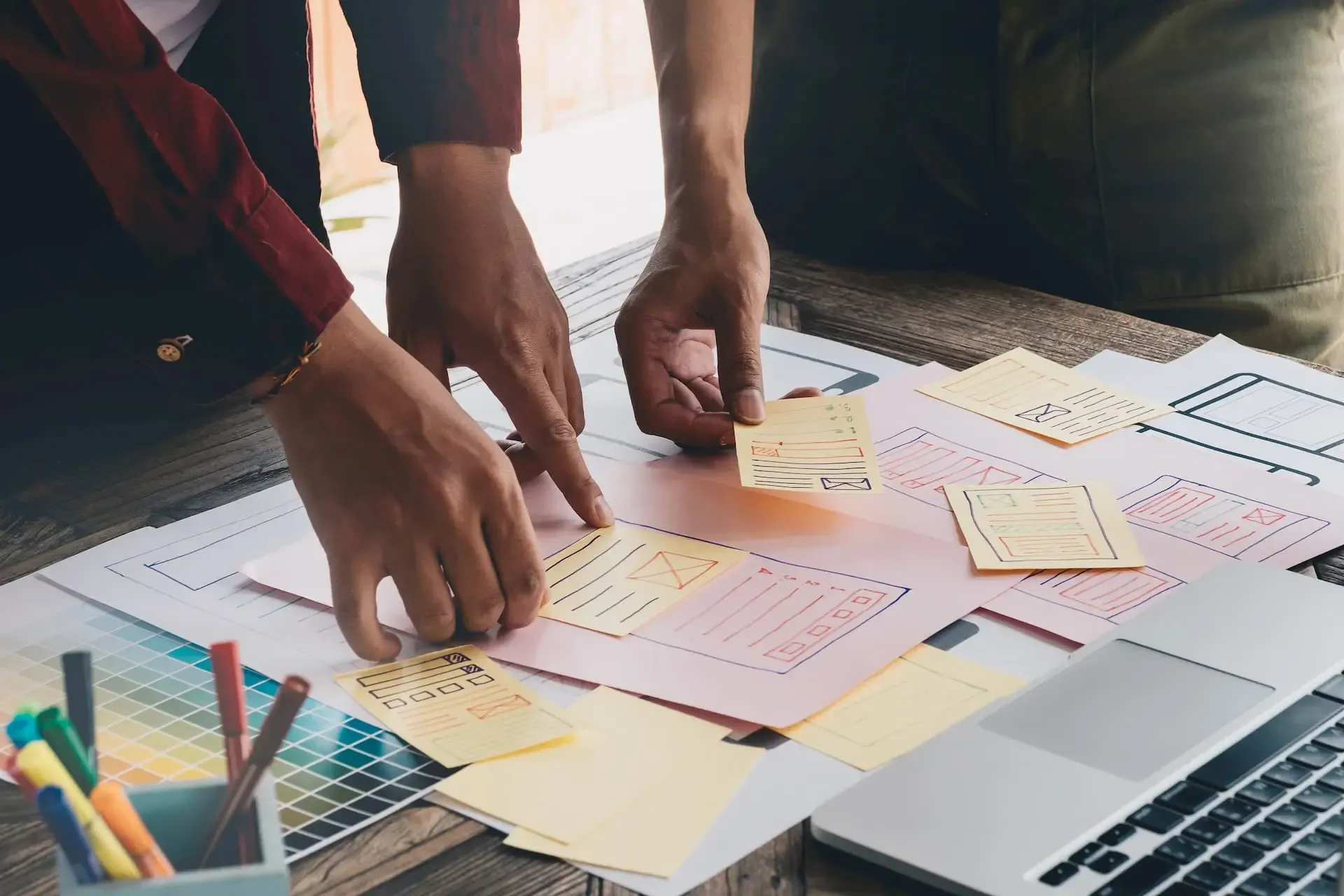 Mitarbeitende sortieren Post-its auf einem Schreibtisch