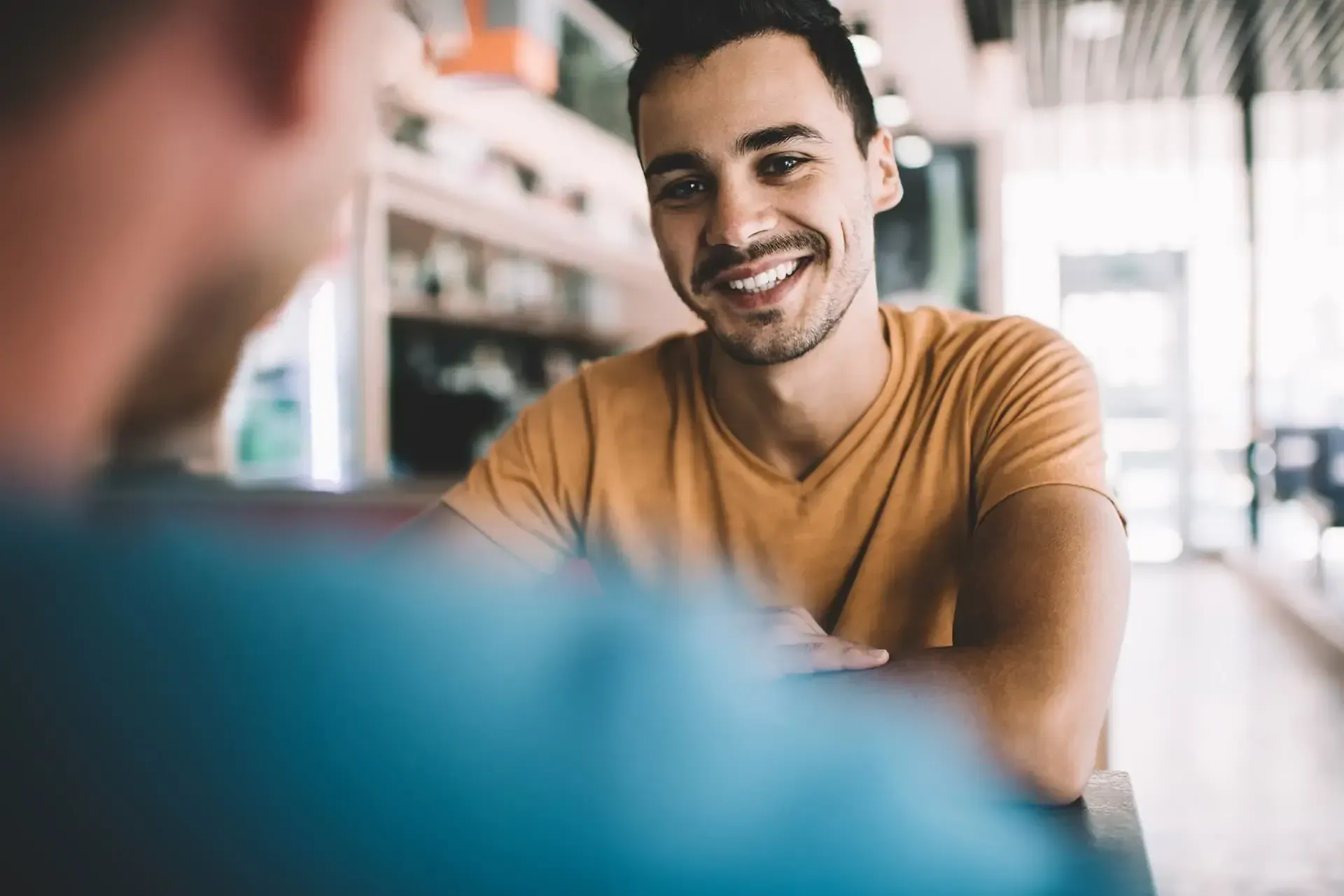 SWK Corporate Language Mann lächelt andere Person an