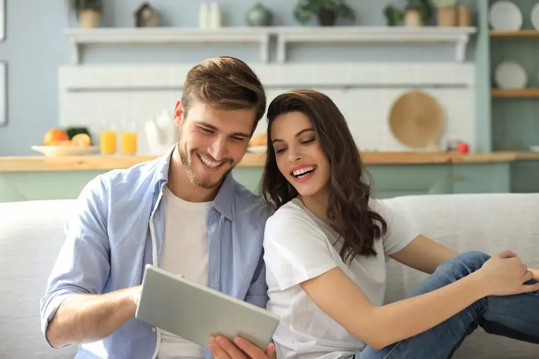 Mann und Frau sitzen nebeneinander und schauen auf einen Laptop