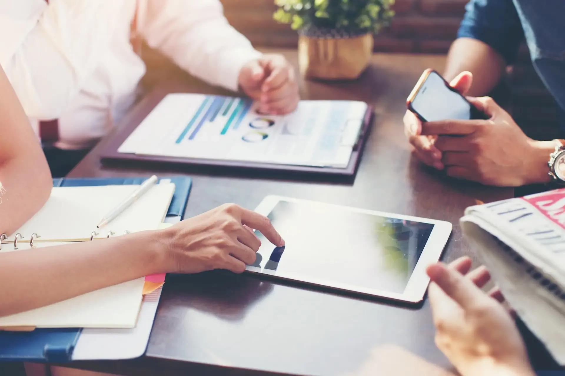 Mitarbeitende mit Tablet und Unterlagen an einem Schreibtisch