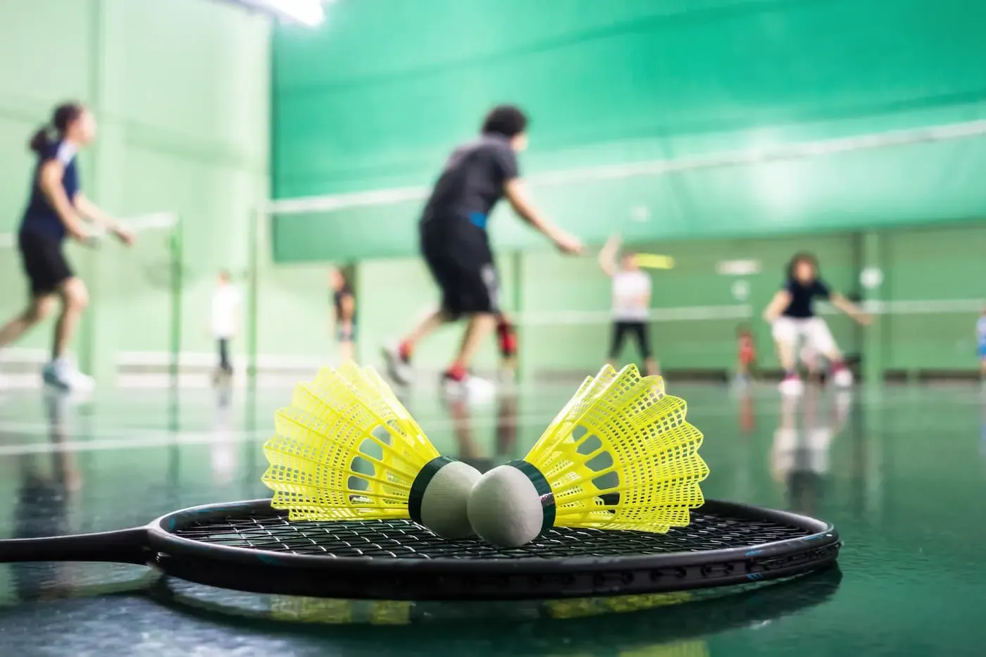 Badminton Schläger mit zwei Bällen liegen im Vordergrund eines Badminton Spiels